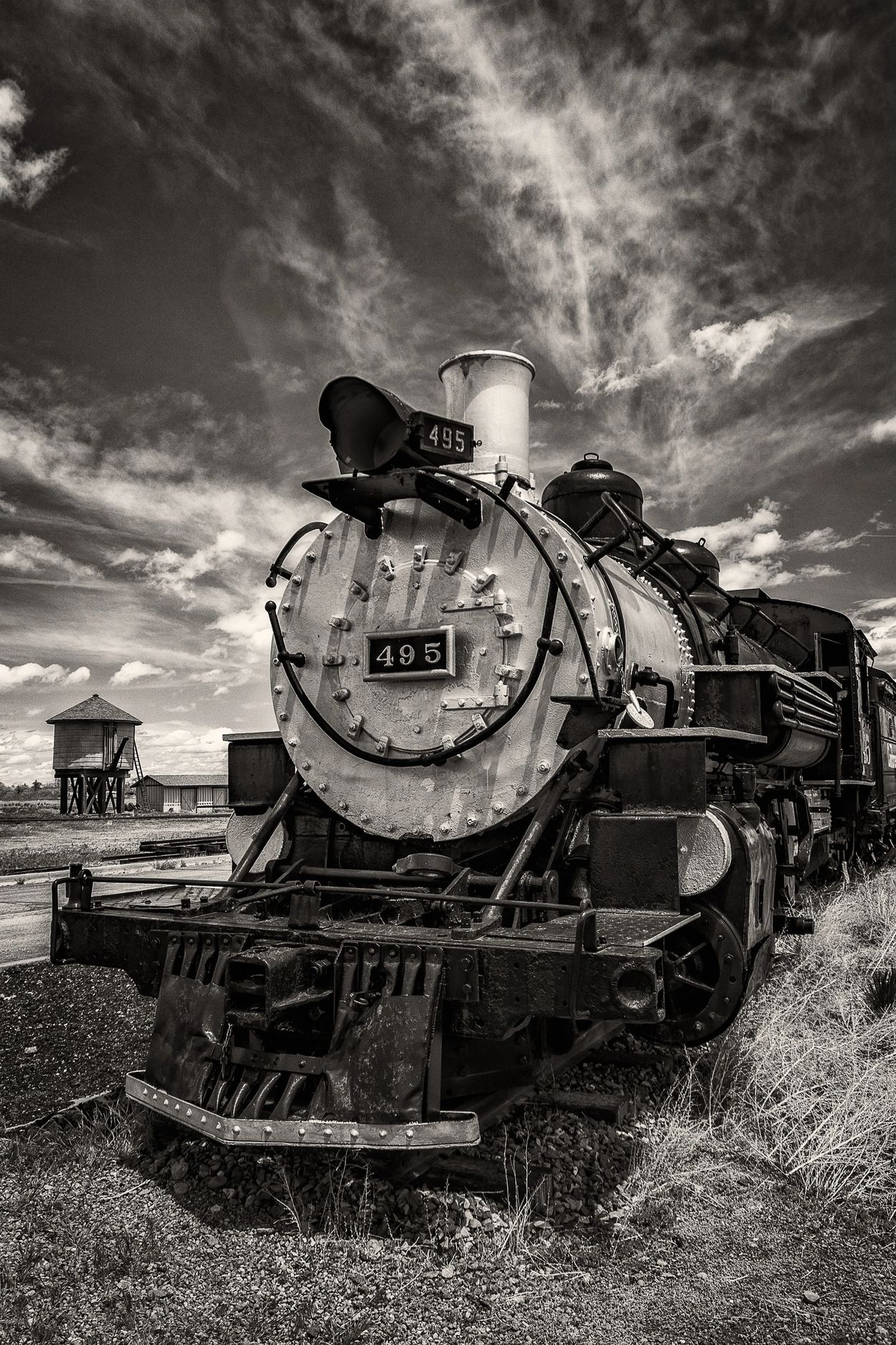 Black and white photo of vintage steam locomotive number 495 under dramatic sky.