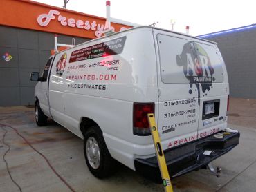 White ASR Painting van parked outside an orange building.