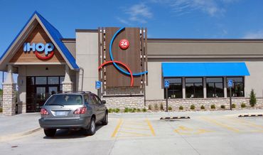 Front view of an IHOP restaurant with a car in the parking lot.