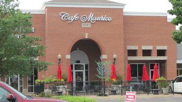 Cafe Maurice exterior with red umbrellas.