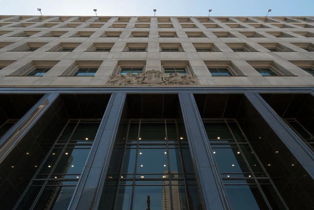 Low-angle view of a tall building with many windows and reflective glass panels.