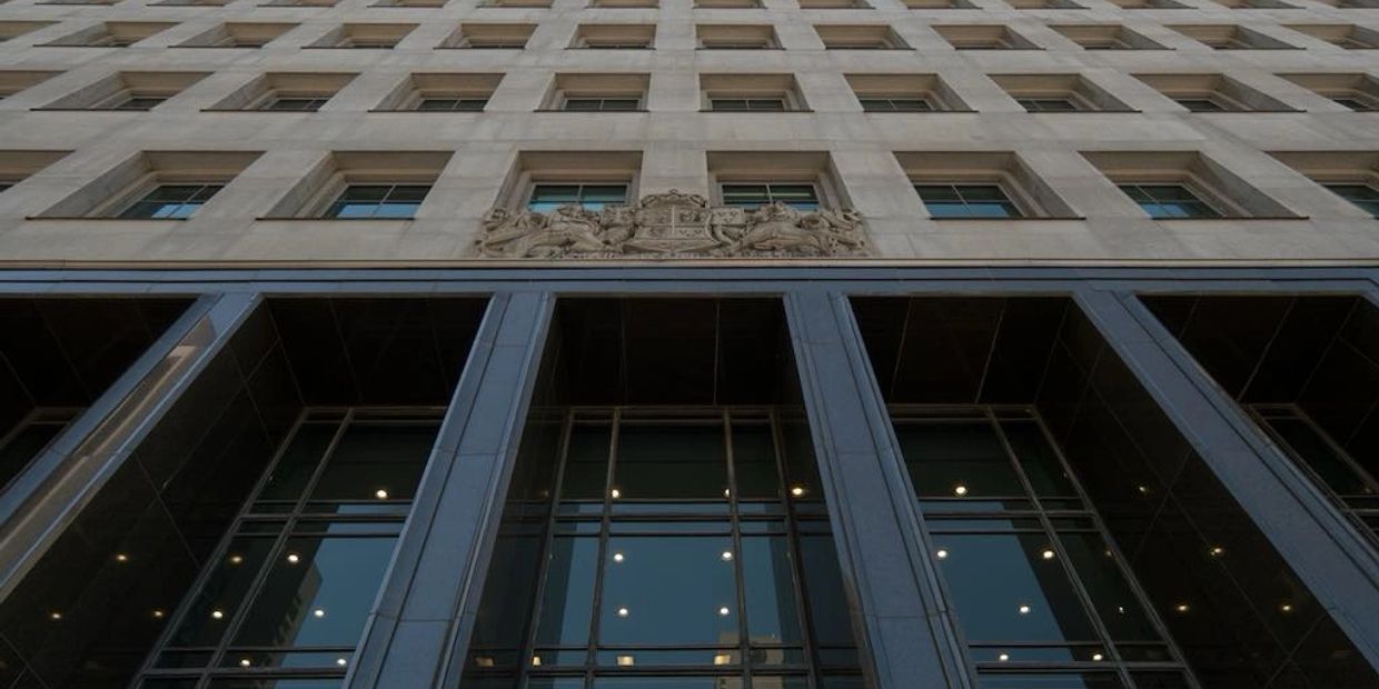 Low-angle view of a tall building with many windows and reflective glass panels.