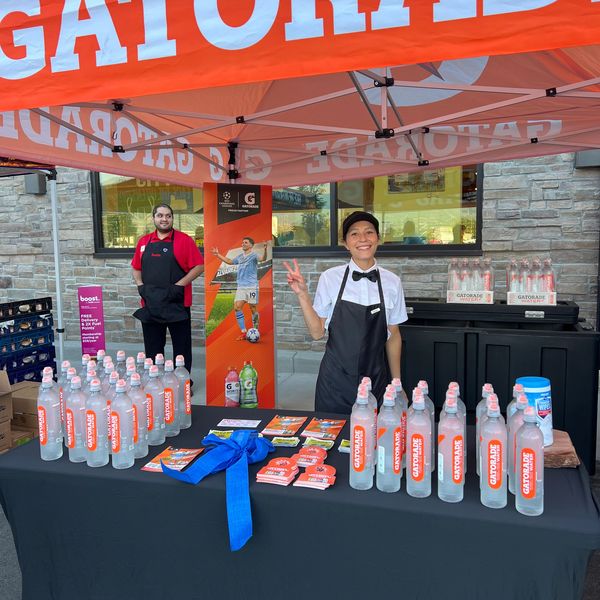 Two smiling workers stand behind a table with Gatorade bottles and promotional materials.