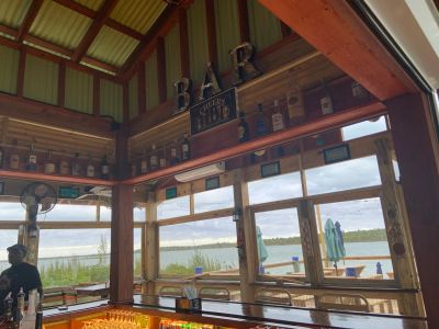 Rustic bar with lake view and bottles on the shelf.