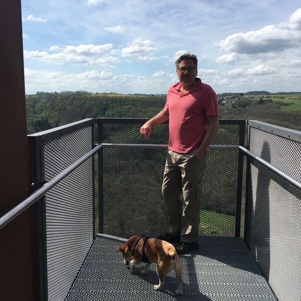 Mann mit Hund auf der Aussichtsplattform Siebenbachblick auf dem Erlebnisweg Achterhöhe in Lutzerath