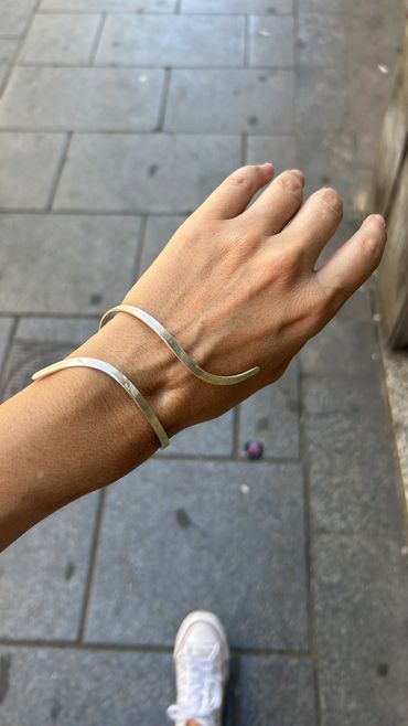 Pulsera plateada en la muñeca de una mano.