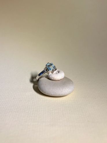 Anillo con piedra azul sobre piedras lisas.
