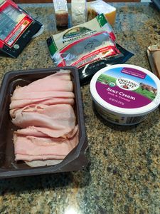 Sliced ham and sour cream on a kitchen counter.