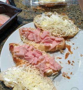 Open-faced sandwiches with ham and shredded cheese.