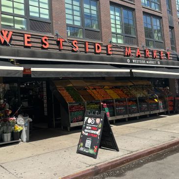 Exterior of Westside Market with fresh produce displayed outside.