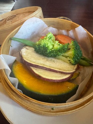 Steamed mixed vegetables in a bamboo basket.
