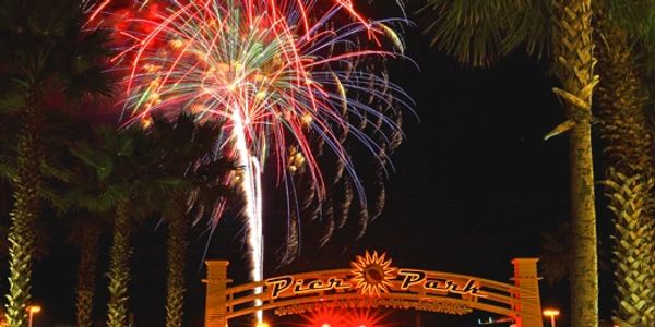Colorful fireworks explode over Pier Park at night.