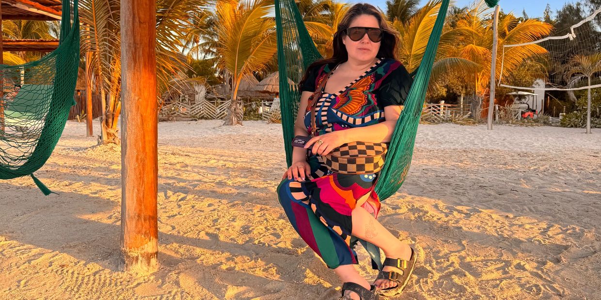 Olivia Rodriguez, AKA Mommy Day Drinks sitting on a swing on the beach in Mexico.