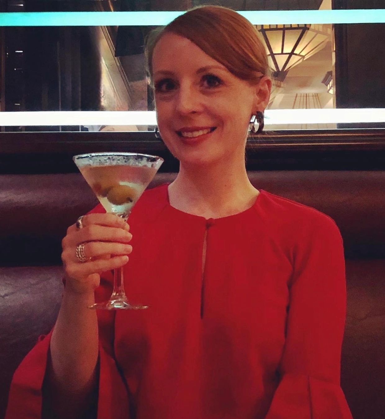 Woman in a red dress holding a martini glass with olives.