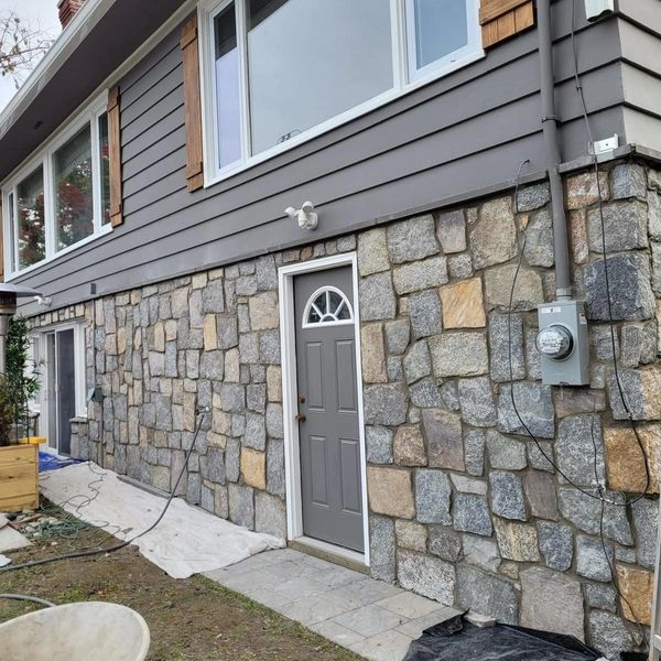 House exterior with stone siding and a gray door.