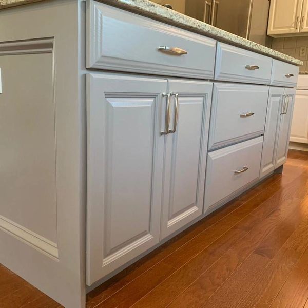 White kitchen cabinets with silver handles over wooden floor.