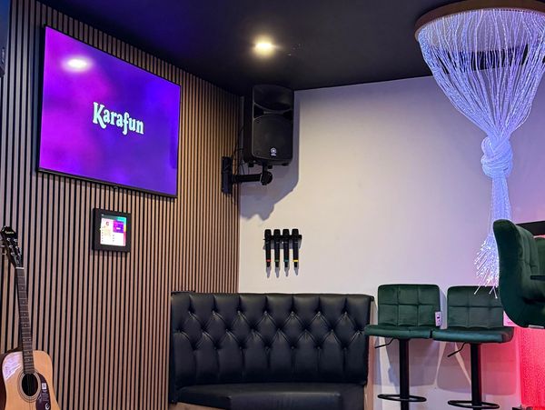 Cozy karaoke room with a guitar, microphone set, and comfortable seating.