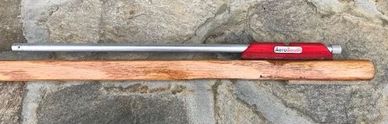 A long metal tool with a wooden handle lying on stone ground.