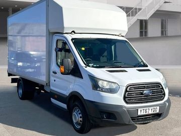 White Ford Transit box truck parked in an urban area.