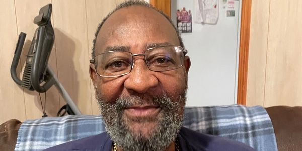 Smiling man with glasses and a beard sitting indoors.