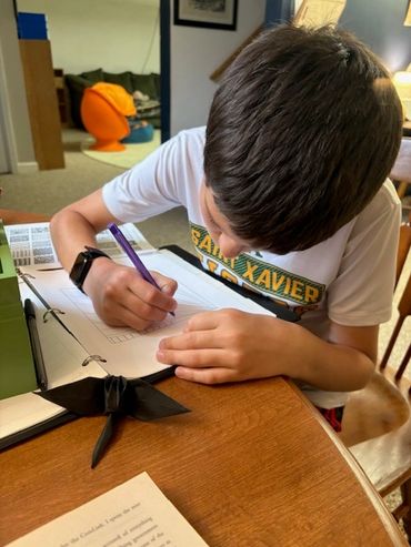 Boy focused on writing in a notebook.
