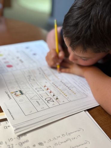 Child focused on completing their homework with a pencil.