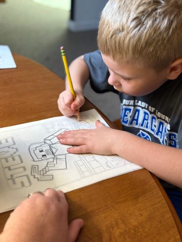 Boy drawing Minecraft character with pencil.