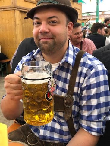 Man in traditional Bavarian attire holding a large beer stein.