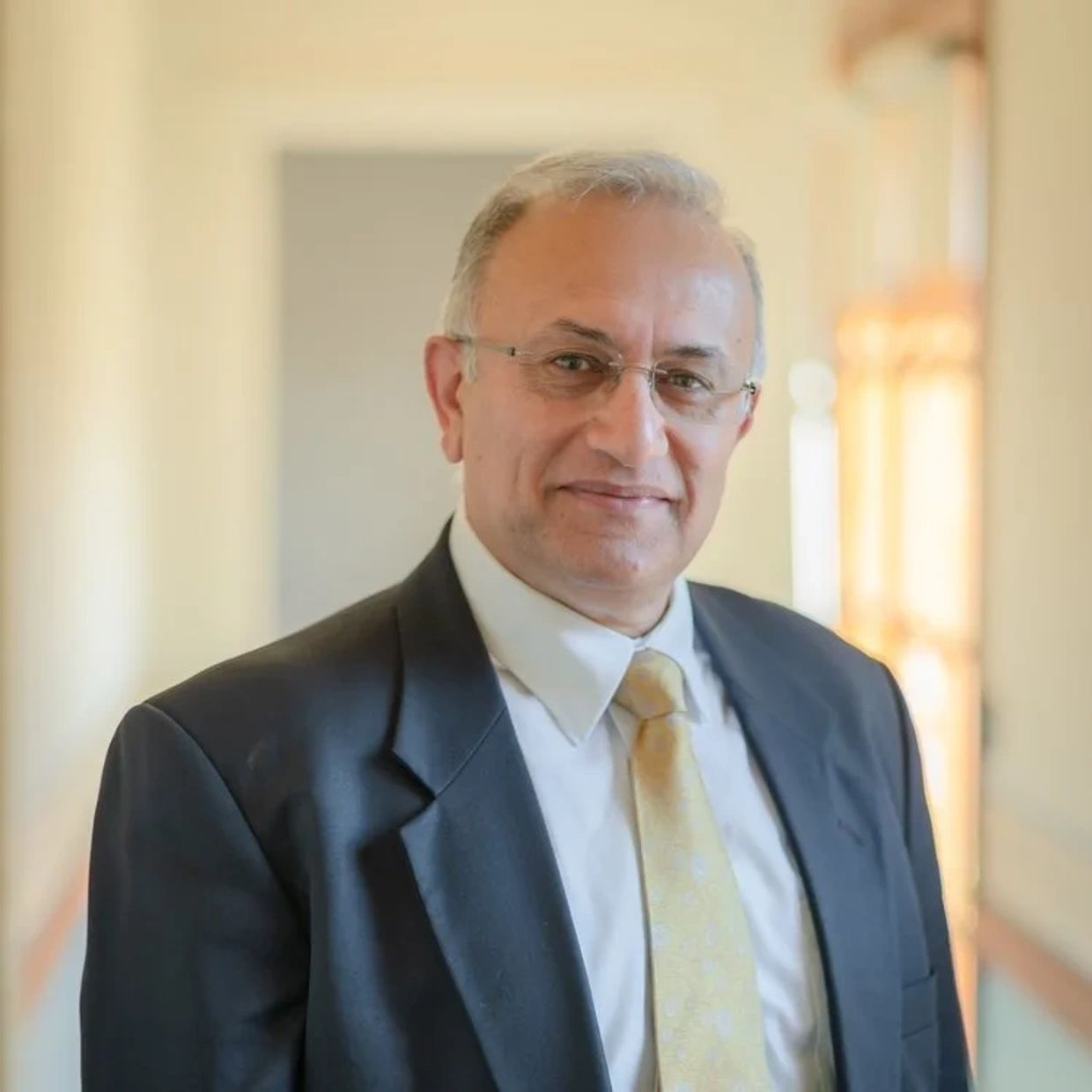 Professional man in suit and tie smiling indoors.