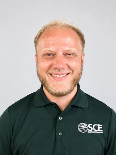 Smiling man wearing a black SCE polo shirt.