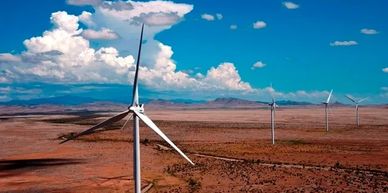 Wind turbines in a desert landscape under a blue sky.