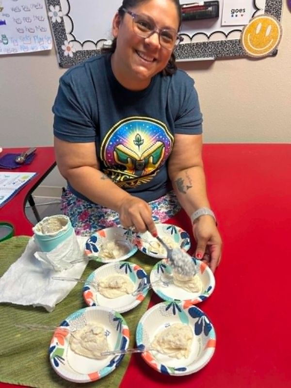Woman smiling while serving food on paper plates.