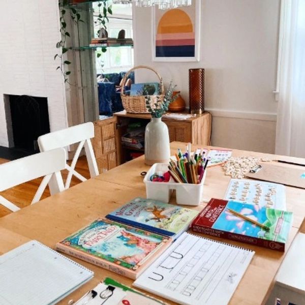 A cozy study table with books, pencils, and learning sheets in a bright room.