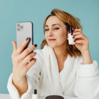 A woman promotes a product (nail polish) via social media on her mobile device.