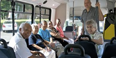A group of elderly people enjoying a bus ride together.