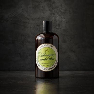 Botella de champú anticaída sobre fondo oscuro.