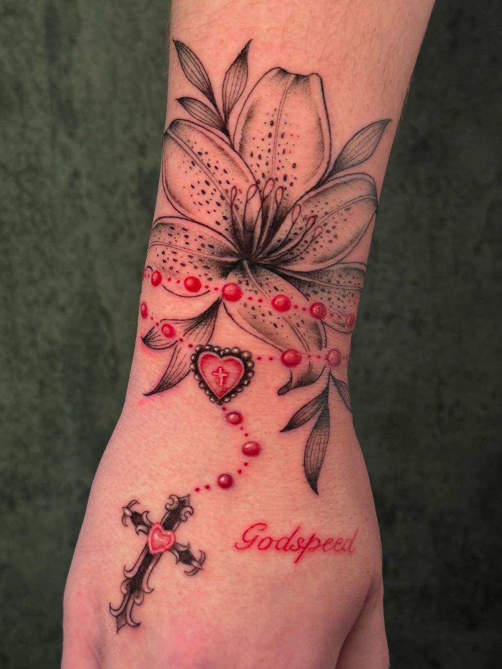 Rosary tattoo with flower and text on hand.
