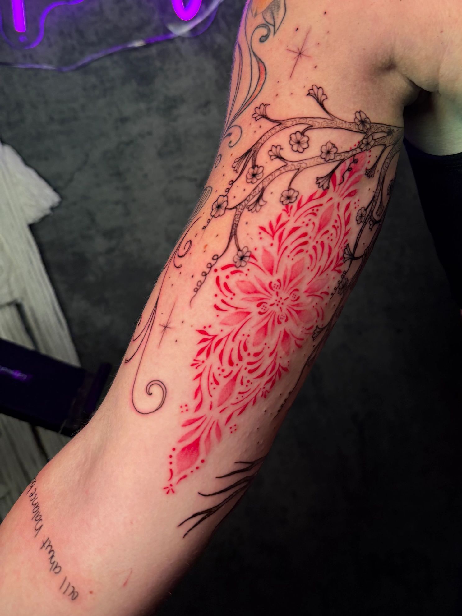 Floral tattoo with red and black ink on forearm.
