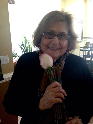 Elderly woman smiling with a pink rose.