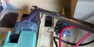 Loose Driver figure held by tweezers in glued in place in a model train locomotive.