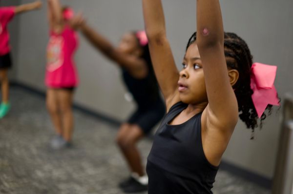Young girls exercising with arms raised, focused and determined.