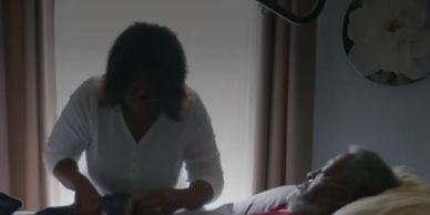 A woman caring for an elderly person in bed.