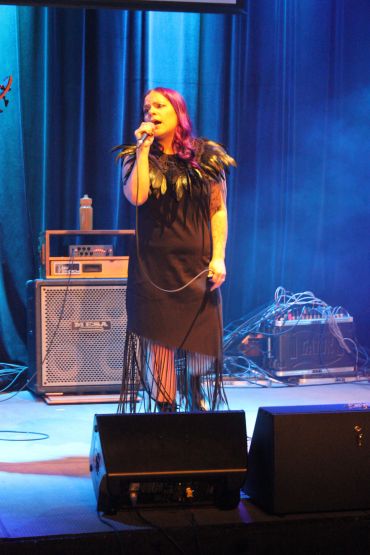 Female singer performing on stage with microphone.