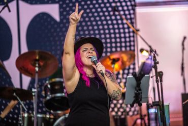 Female singer passionately performing on stage with raised arm.