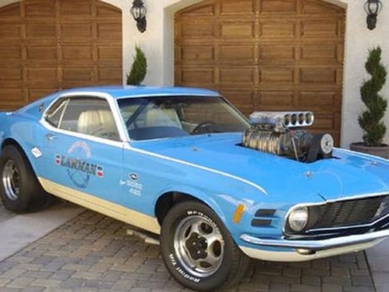 Bright blue classic muscle car with a powerful engine protruding from the hood.