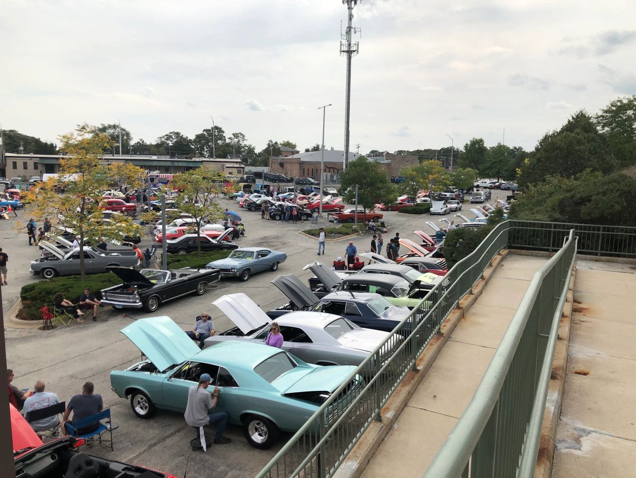 Classic car show with many vintage cars and spectators in an outdoor parking lot.