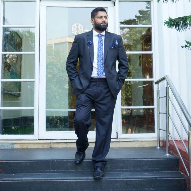 Man in black suit descending stairs outside a glass door.