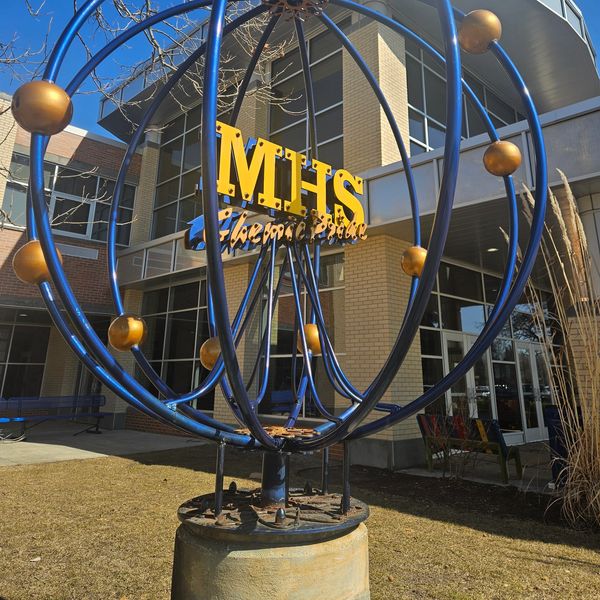 Sculpture outside a modern building labeled MHS.