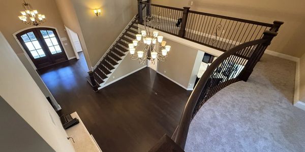 Spacious two-story foyer with dark hardwood floors and elegant chandeliers.