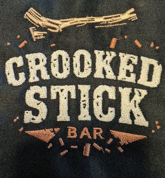 Embroidered logo of Crooked Stick Bar with a crooked stick design.